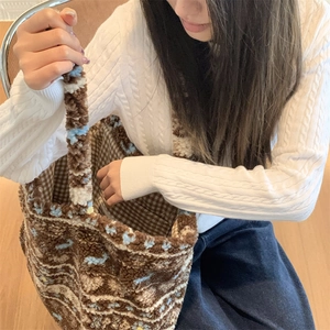 Detail of plush brown and beige tote bag with blue floral patterns and checked lining