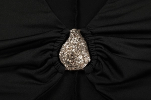 Detail of elegant gold hammered metal buckle on black dress with pleated neckline