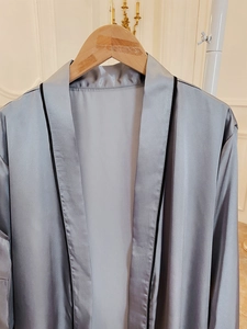 Detailed close-up of silver satin robe featuring smooth texture and black trim edges