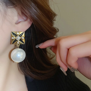 Detail of vintage square crystal earrings with large white pearls on a female model
