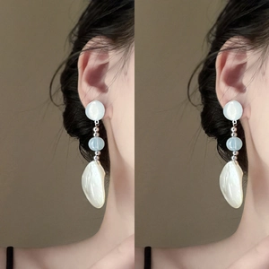 Detail of elegant drop earrings featuring light blue beads and white shell pendants