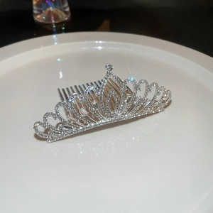 Peigne à cheveux couronne argentée avec strass scintillants sur un plateau blanc