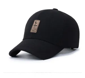 Detail of black wool baseball cap featuring a brown leather patch and thick stitching