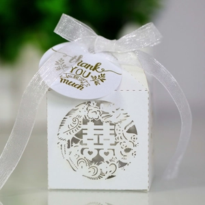 Detail of white laser-cut Chinese wedding candy box with dragon phoenix motif and silk ribbon