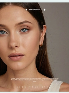 Close-up of a stylish gold dachshund hoop earring worn by a model in a natural setting