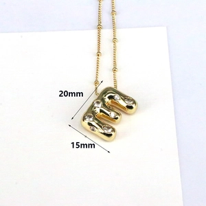 Detail of 18k gold bubble letter E pendant with zircon stones, 20mm height macro view