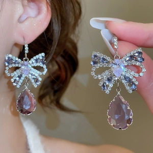 Detail of silver bow earrings with sparkling purple crystal teardrop pendants