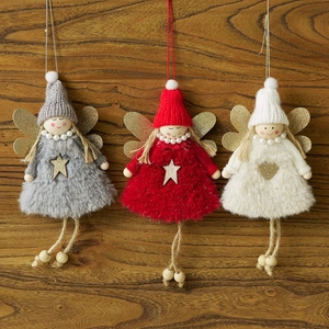 Three plush Christmas angel ornaments with wooden heads and glittery gold wings on wood