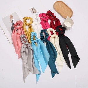 Set of 10 colorful satin silk hair scrunchies with long ribbons on an elegant white table