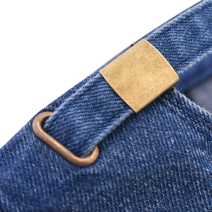 Detailed macro view of the vintage bronze buckle and navy denim strap on baseball cap