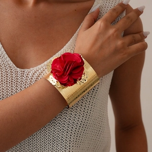 Metallic gold wide cuff bracelet with large red fabric flower on female model's arm