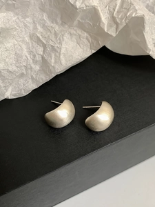 Close-up of minimalist gold matte geometric earrings on a black surface