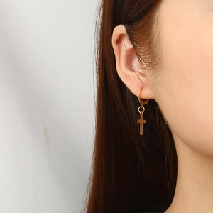 Boucles d'oreilles créoles croix en acier plaqué or 18 carats portées par un mannequin