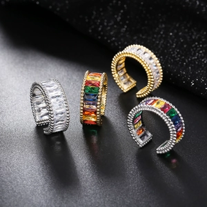 Macro shot of gold and silver rings with rainbow baguette crystals on black glitter background