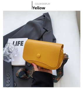 Detail of yellow pebbled leather crossbody bag with Bohemian style patterned wide strap