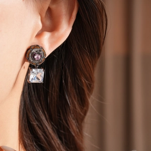 Detail of vintage flower earring with pink gem and large square zircon on model