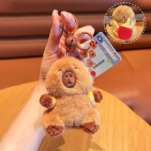 Close-up of plush capybara keychain with red ping-pong racket backpack and bell