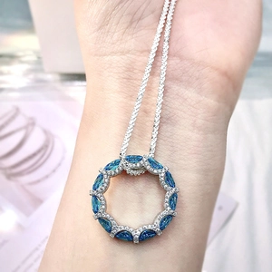 Detailed close-up of a silver necklace featuring a blue marquise gemstone pendant