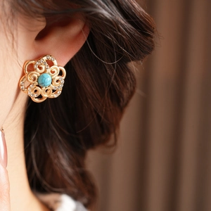 Detail of vintage gold flower earring with turquoise center and rhinestones on model