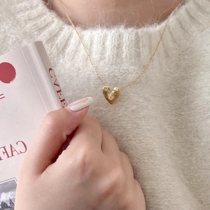 Detailed close-up of a 3D irregular gold heart pendant on a fine necklace chain