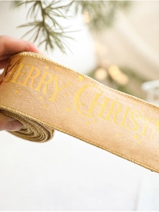 Close-up of champagne gold Christmas ribbon with Merry Christmas gold foil lettering