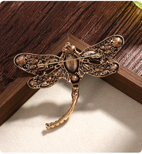 Detailed back view of vintage dragonfly brooch with safety pin clasp on velvet background