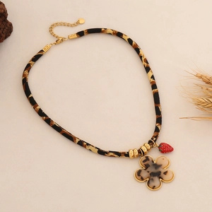 Dettaglio della collana in tessuto leopardato con pendente a fiore e ciondolo fragola