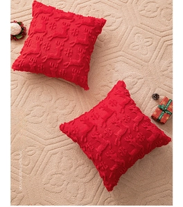 Detail of red Christmas pillow covers with embroidered reindeer and snowflake patterns