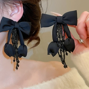 Detail of elegant black fabric bow earrings with crystal tassel and bead drops