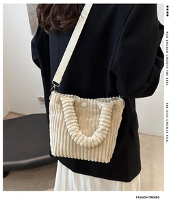 Detail of cream corduroy bucket bag with pleated handle and detachable strap on a model