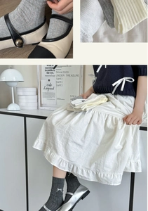 Detail of grey ballet-style cotton socks featuring vertical stripes and cute bow accents