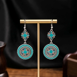 Detail view of retro Bohemian turquoise sunflower earrings on a black velvet background