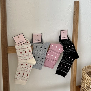Détail du tricot de chaussettes de Noël à motifs de cœur en crème, rose et gris