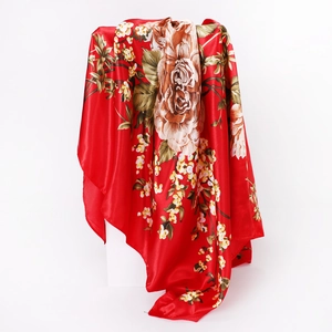 Close-up of red silk scarf with floral paisley print draped over a white minimalist block