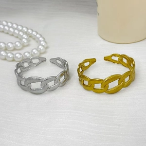Poliertes gold- und silberfarbenes Gliederketten-Armband auf strukturiertem weißem Stoff