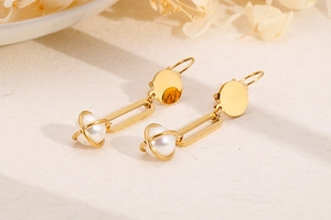 Detailed macro view of long drop earrings with pearl inside a golden wire cage