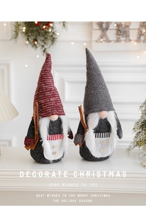 Close-up of knit Christmas gnomes in red and grey hats on a festive white table