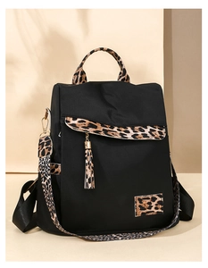 Detail of black oxford backpack featuring leopard print straps and tassel accessories
