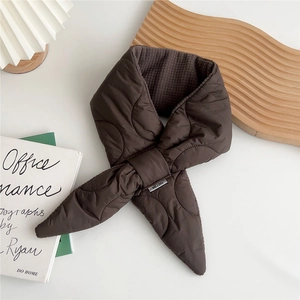Close-up of brown quilted down scarf with cross strap design and brand label detail