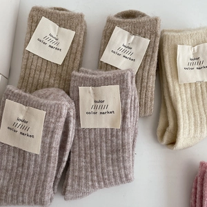 Detail of knit wool socks in neutral tones showing ribbed texture and fabric labels