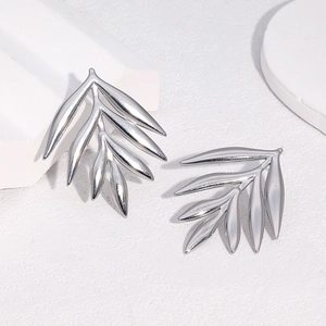 Vue macro de boucles d'oreilles argentées en forme de feuille en acier poli