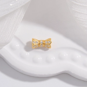Close-up of golden bow pendant with micro-pave white zircons for jewelry making