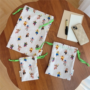 Detailed set of three drawstring cotton pouches with colorful bear prints on wood