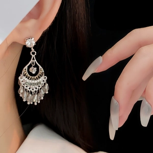 Détails de boucles d'oreilles bohèmes avec cristaux en goutte et motifs argentés ajourés