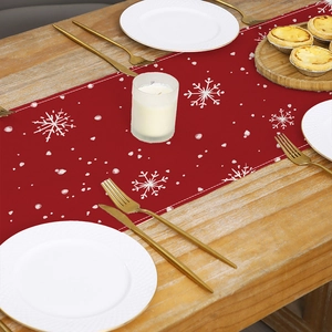 Christmas table runner with white snowflake prints on red fabric on wooden dining table