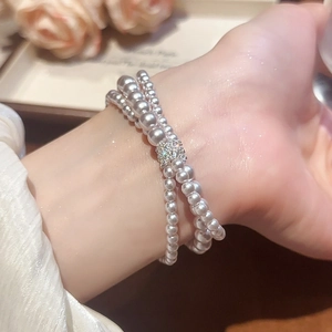 Close-up of triple-layer pearl bracelet with micro-paved zircon bead on female wrist