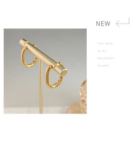 Detail of gold U-shaped oval hoop earrings hanging on a metallic display stand