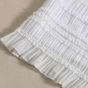 Détail de robe blanche avec volants superposés et tissu plissé à texture fine