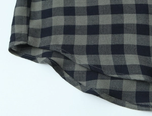 Macro view of a curved hem on a black and grey checkered shirt with twill texture
