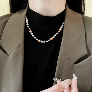 Gros plan d'un collier de perles multicolores montrant des perles dorées et grises sur un mannequin